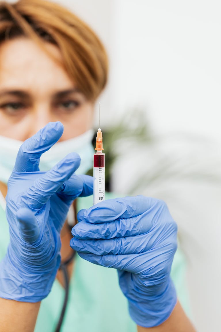 Nurse in gloves preparing a syringe filled with liquid, ready for medical procedure.